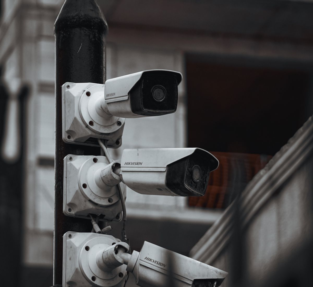 Trois caméras de vidéosurveillance fixées sur un mât, en façade d’un bâtiment industriel